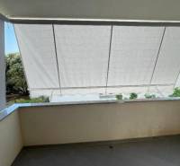 Balcony of a 3-room apartment in Novalja with retracted awnings and a view of the garden.
