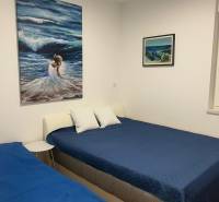 Bedroom in a 3-room apartment with blue beds, white pillows, and paintings on the wall.