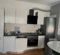 A kitchen with white cabinets, a stainless steel refrigerator, wood-patterned flooring, 3-room apartment.