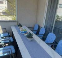 A balcony in a 3-room apartment with a table, seating, and decorations, ideal for relaxation.
