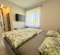 A bedroom in a family house with a wardrobe, a television, and a bed with tropical patterned bedding.