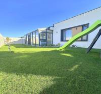 A family house in Mosonmagyaróvár with a glass veranda and a green slide in the garden.