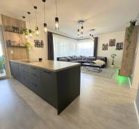 A kitchen with an island and a living room in a family house with a comfortable sofa.