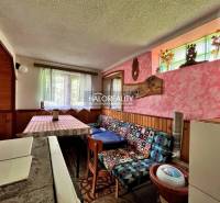 The interior of a cabin with wooden paneling, a colorful sofa, and a striped tablecloth.