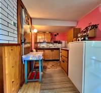 A kitchen in a cottage with a wooden decor floor and pink walls.