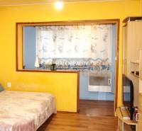 Yellow walls and curtains with a children's motif in a studio apartment, floor with wooden decor.