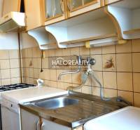 A kitchen in a studio apartment with a gas stove, tiled backsplash, and storage cabinets.