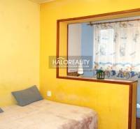 Yellow walls and a bed with pillows in a studio apartment.