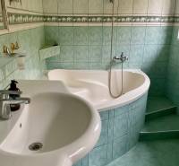 A bathroom with a corner bathtub and green tiles on recreational grounds.