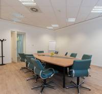 Conference room with wood-patterned flooring, a round table, and green chairs.