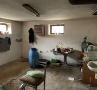 A room in a family house with peeling plaster and various furniture looks neglected.
