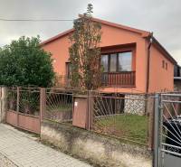 A family house in Lúčnica nad Žitavou with an orange facade, a garden, and a decorative fence.