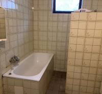 A bathroom in a family house with a white bathtub and tiled walls.