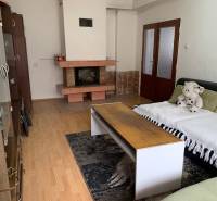 Living room in a family house with a fireplace, wooden decor flooring, and a comfortable couch.