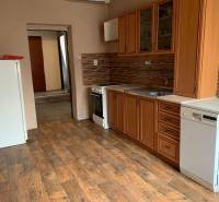 A kitchen in a family house with a wooden decor floor and brown cabinets.