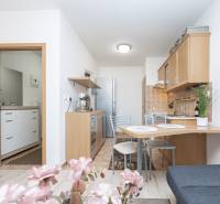 A kitchen in a 2-room apartment with a dining table, light cabinets, and flowers on the table.