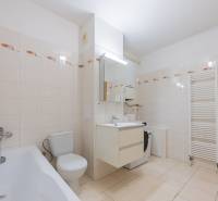 Bathroom with a bathtub, sink, and washing machine in a 2-room apartment. Flat tiles with a floral pattern.