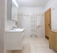 A bathroom in a 2-room apartment with a white washbasin cabinet and a wooden chest of drawers.