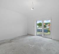 An empty room with a concrete floor and large French doors in a family house.
