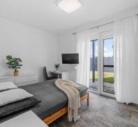 A bedroom in a family house with a bed, a television, and patio doors.