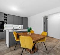 A kitchen in a family house with a dining table and yellow chairs, a floor with a wooden decor.