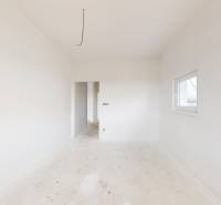 A spacious bright room in a family house with white walls and a smaller window.