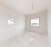 Empty room with light walls and two windows in a family house.