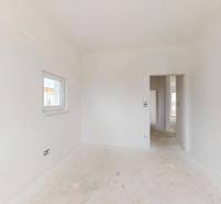An empty white interior in a family house with a window and door without flooring with wooden decor.