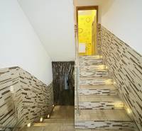 A staircase in a family house with cladding and lighting, leading to the upper floor.