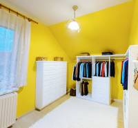 A wardrobe in a family house with colorful walls, white furniture, and a curtain.