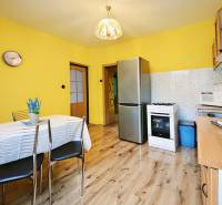 A kitchen in a family house with a wooden decor floor, yellow walls, and appliances.