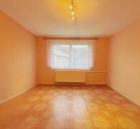 A room in a family house with orange walls and a wooden decor floor.