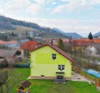 A family house in Kysucké Nové Mesto surrounded by a garden and mountains in the background.