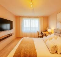 Bright bedroom in a family house with a TV, a desk, and a comfortable bed.