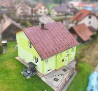 A family house in Kysucké Nové Mesto with a green facade and a metal roof.