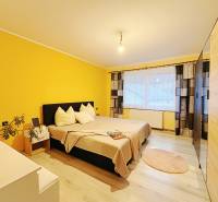 A bedroom in a family house with a wood-patterned floor and yellow walls.
