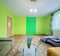 Living room in a family house with colorful walls, a sofa, and a large carpet.