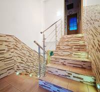 A staircase with stone decor and stainless steel railing in a family house.