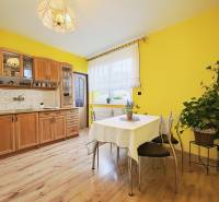 A kitchen in a family house with yellow walls and a wooden decor floor.