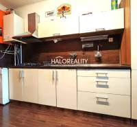 A kitchen with a washing machine, kitchen unit, and wooden decor flooring in a 4-room apartment.