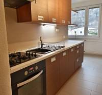 A kitchen in a 2-room apartment with a cooktop, oven, and a window with a view.