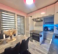 A kitchen in a 3-room apartment with a modern kitchen unit, table, and floor with a wooden decor.