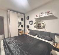 A bedroom in a 3-room apartment with a bed, a wardrobe, and shelves.