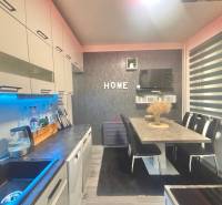 A kitchen in a 3-room apartment with a wooden decor floor, a dining table with chairs.