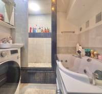 A bathroom with a washing machine, sink, and whirlpool bathtub in a 3-room apartment.