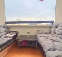 A covered balcony in a 3-room apartment with comfortable seating and a table.