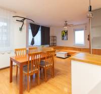 Living room in a one-bedroom apartment with wood-patterned flooring, seating, and a dining table.