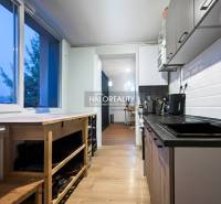 Kitchen in a 3-room apartment with a wood-patterned floor, white tiles, compact interior.