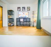 Living room of a three-room apartment with a light wood-patterned floor and a television.