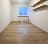 A room in a 3-room apartment with a wooden decor floor and shelves on the wall.
